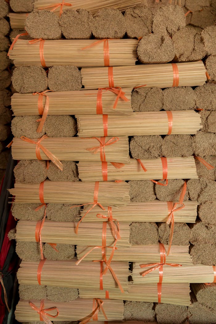 Bundles of neatly stacked traditional incense sticks tied with orange ribbons, ready for shipping.
